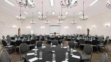A conference room with round tables, chairs, and chandeliers.