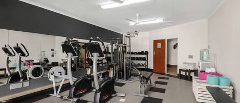 A gym with exercise equipment, a mirror, and a water dispenser.