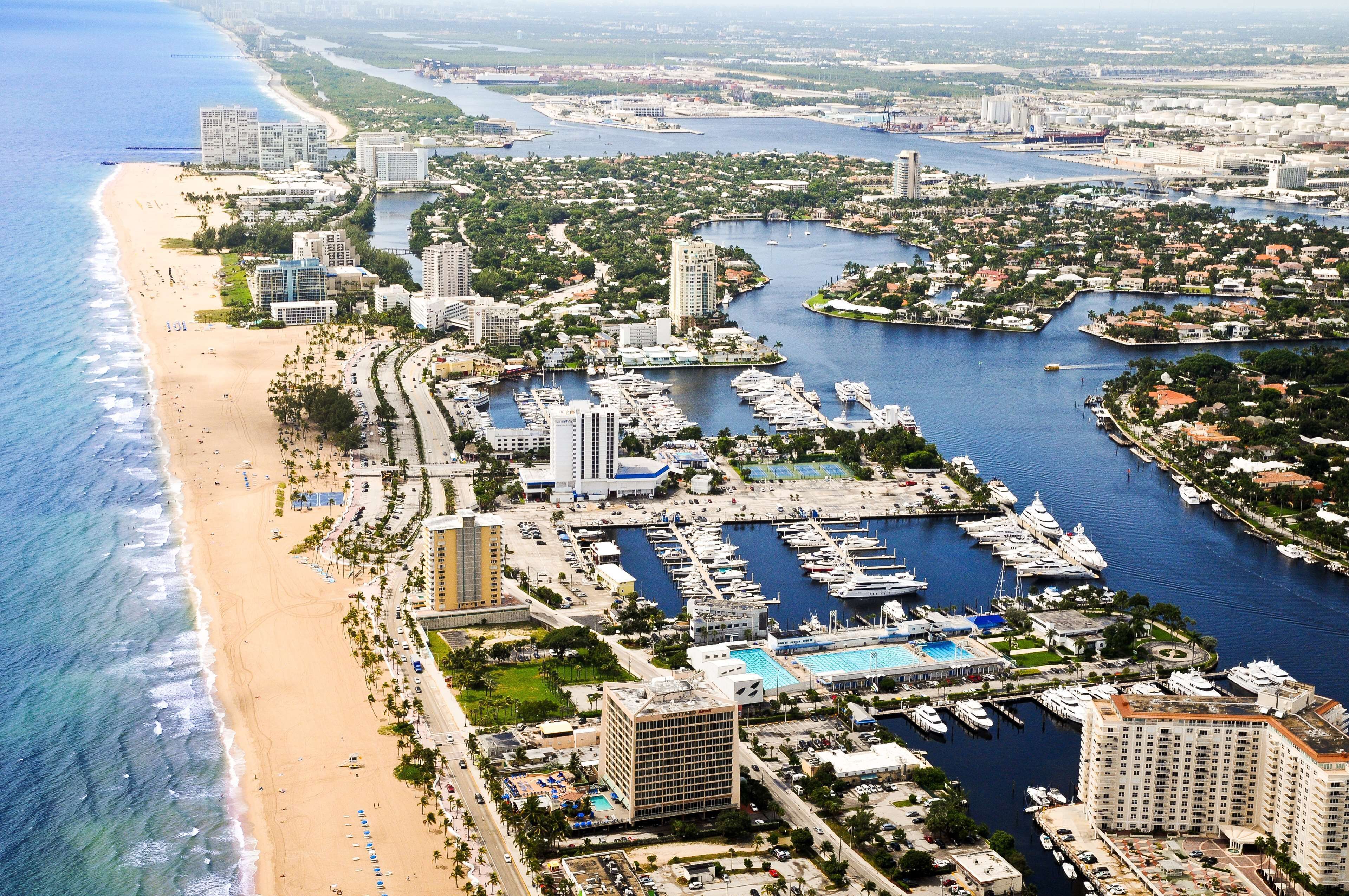 An aerial view of a coastal city with a marina, beach, and high-rise buildings.
