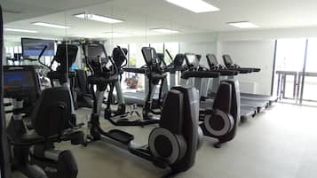 Un gimnasio con cintas de correr, elípticas y máquinas de pesas.
