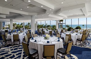 A banquet hall with round tables set for dining, large windows offering a view of the beach and palm trees, and a high ceiling with recessed lighting. - Bahia Mar Ft. Lauderdale Beach- a DoubleTree by Hilton Hotel (Fort Lauderdale)