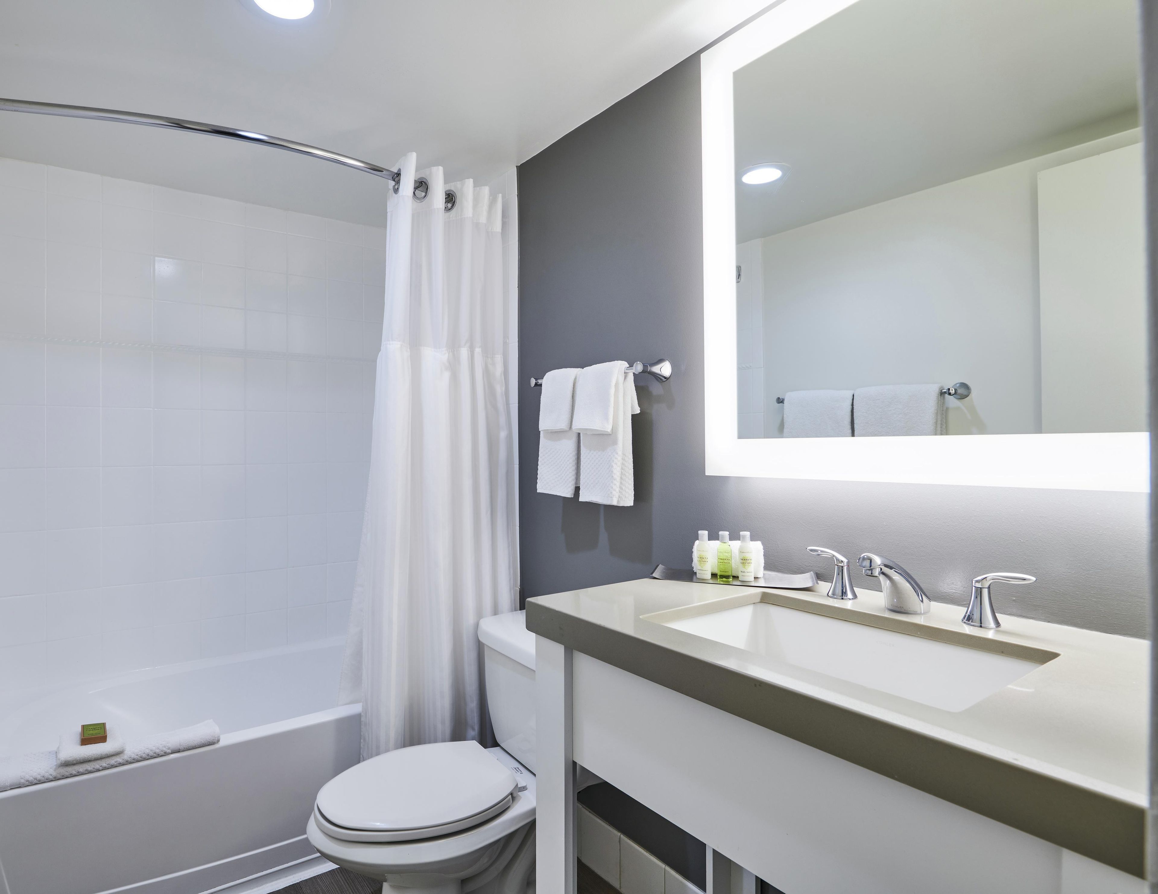 Een moderne badkamer met een bad, toilet en wastafel met spiegel.
