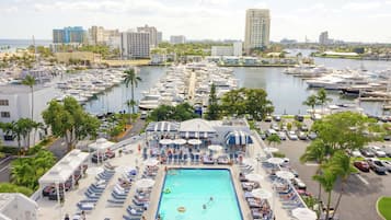 A marina with boats, a swimming pool, and lounge areas with umbrellas.