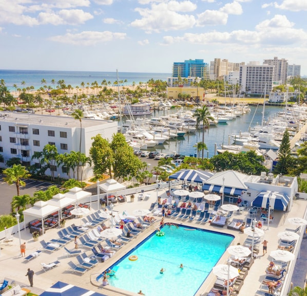 A resort with a swimming pool, lounge chairs, and a marina with boats.