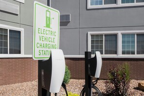 An electric vehicle charging station sign and two Tesla charging units. - Four Points by Sheraton Rock Springs (Rock Springs)