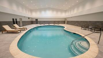 Una piscina techada, sillones reclinables de piscina