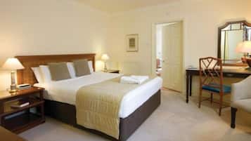 A neatly arranged hotel room with a large bed, bedside tables with lamps, a desk, and a chair.