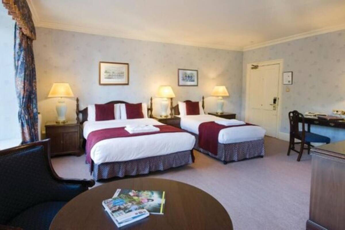 A hotel room with two beds, a desk, and a chair.