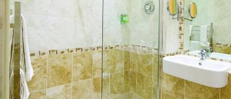 A modern bathroom with a glass-enclosed shower, a white sink, and beige tiles.