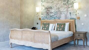 A bedroom with a large bed, a chandelier, a wall mural, and a nightstand.