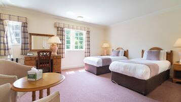 A hotel room with two beds, a desk, a chair, and a round table.