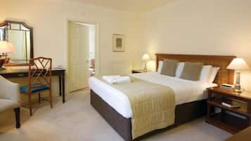 Una habitación de hotel ordenada con una cama grande, mesitas de noche, una silla y un escritorio.