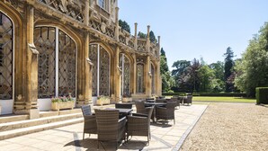 A historic building with ornate architecture, outdoor seating area, and well-maintained garden. - Orton Hall Hotel & Spa (Peterborough)