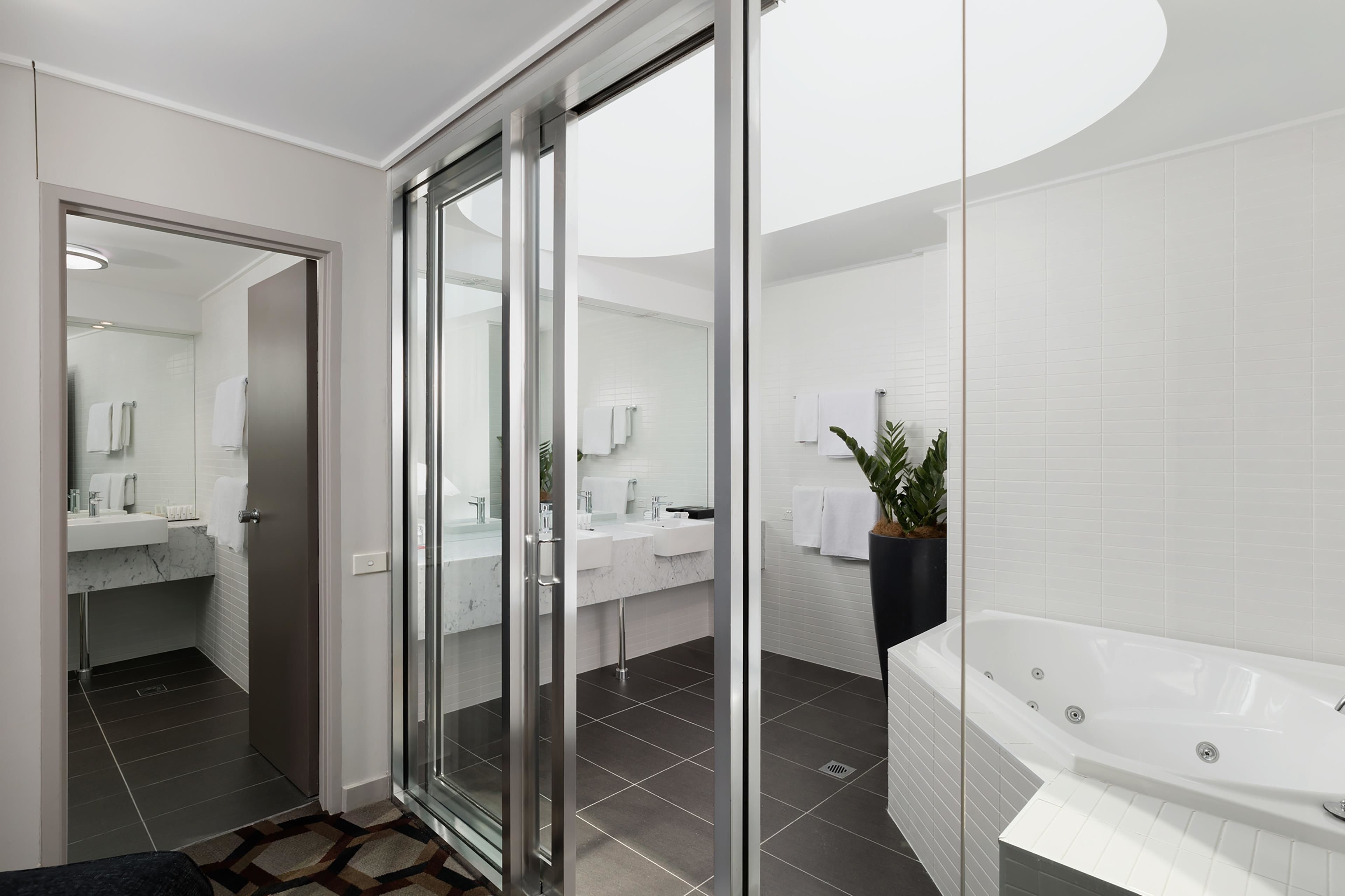 A modern bathroom with a glass shower enclosure, a separate sink area, and a large bathtub.