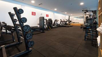 A gym with various exercise equipment, including dumbbells, weight machines, and cardio machines.