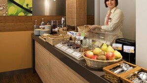 En buffetbod med forskellige retter, en person bag boden og en digital menu.