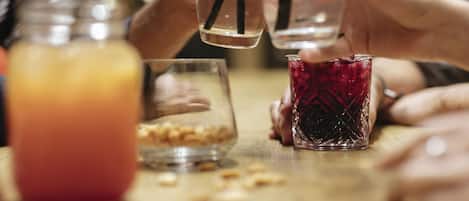 Un groupe de personnes tenant des verres avec des pailles, un bocal contenant une boisson rouge et un verre contenant une boisson jaune.