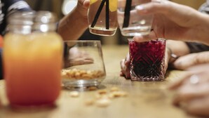 En gruppe mennesker holder glas med sugerør, en krukke med rød drik og et glas med gul drik.