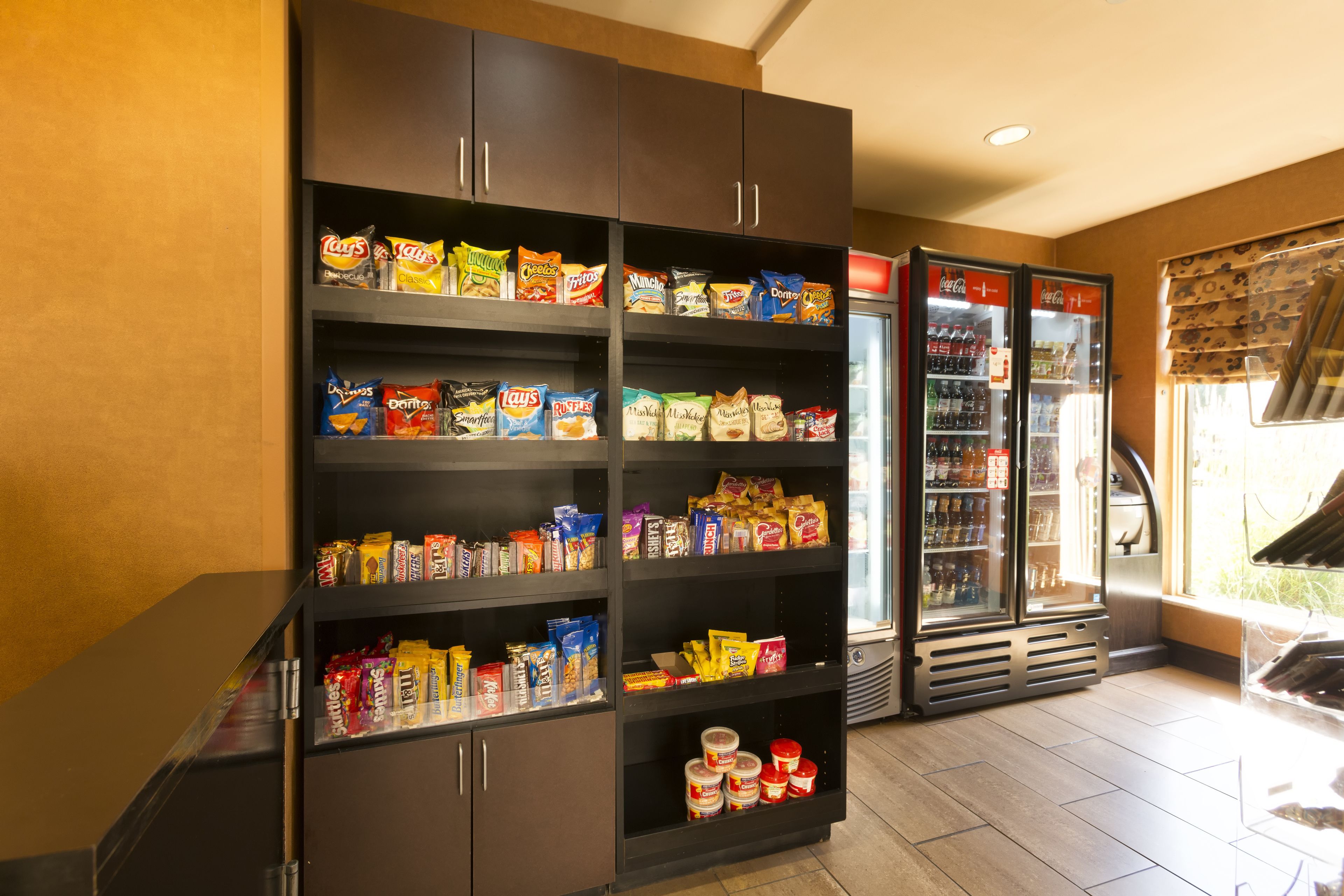 Ein Automatenbereich für Snacks und Getränke mit mehreren Regalen, gefüllt mit verschiedenen Snacks, und zwei Kühlgeräten mit Getränken.