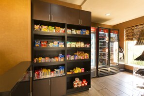 A snack and beverage vending area with multiple shelves stocked with various snacks and two refrigerators containing beverages. - DoubleTree by Hilton Washington Meadow Lands Casino Area (Washington)