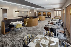 A hotel dining area with round tables, cushioned seating, and a patterned carpet. - DoubleTree by Hilton Washington Meadow Lands Casino Area (Washington)