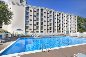 A rectangular swimming pool with a white border and a blue interior. There are metal pool ladders at the shallow end. The pool is surrounded by a white fence with lounge chairs and umbrellas. - DoubleTree by Hilton Washington Meadow Lands Casino Area (Washington)