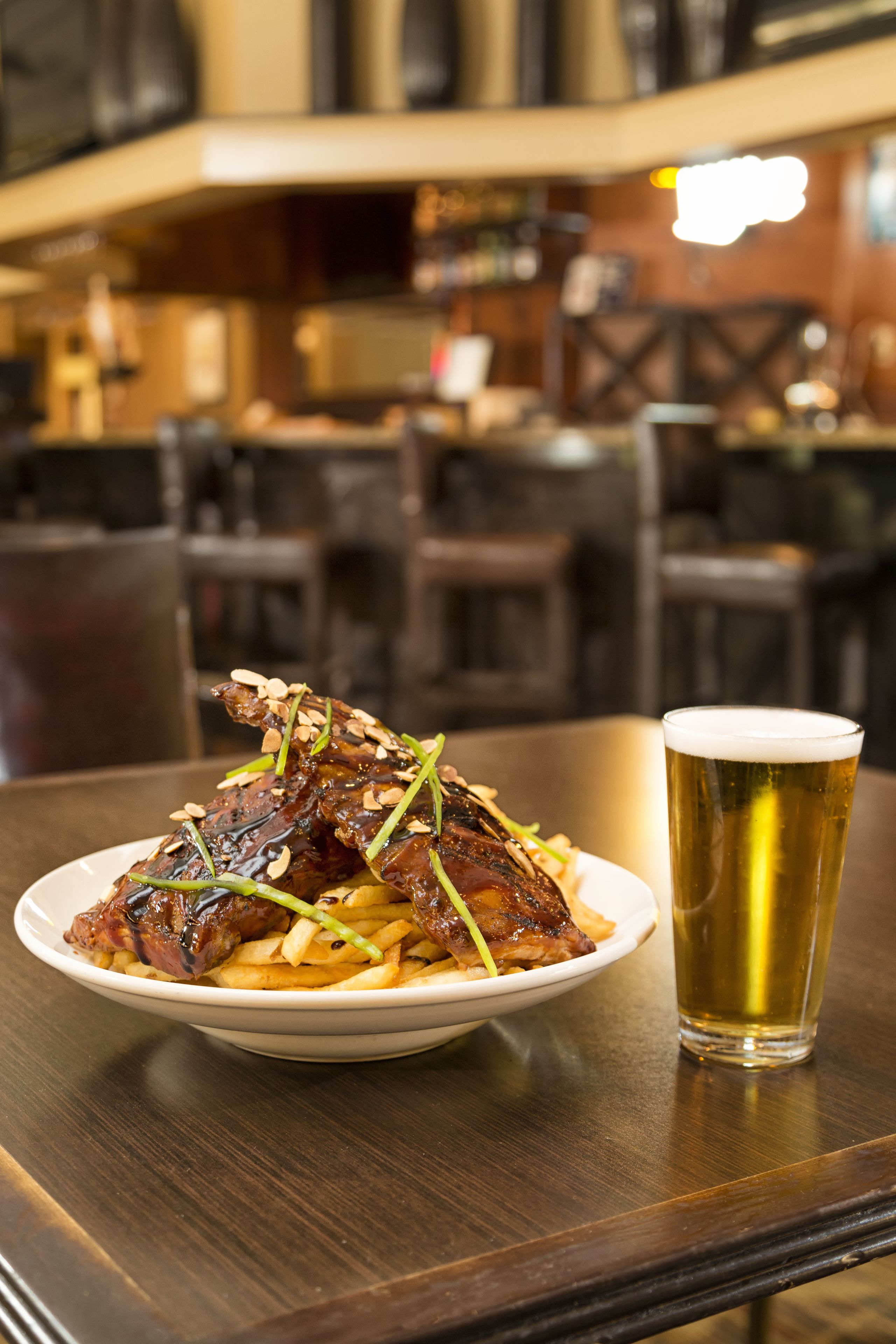 A plate of food with a glass of beer on a wooden table in a restaurant setting.