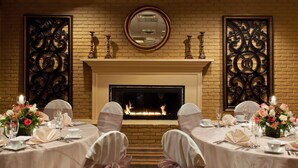 A formal dining room with a fireplace, two side tables with floral arrangements, and chairs with sashes. - DoubleTree by Hilton Washington Meadow Lands Casino Area (Washington)