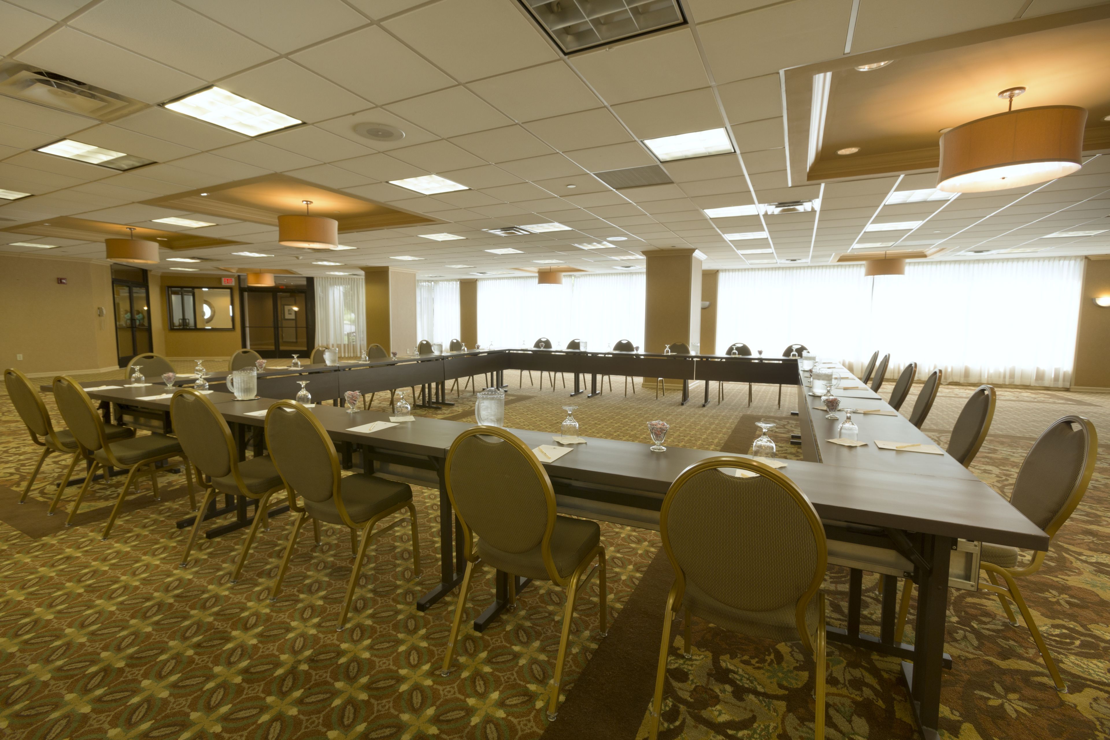 A conference room with a long table, chairs, and a carpeted floor.