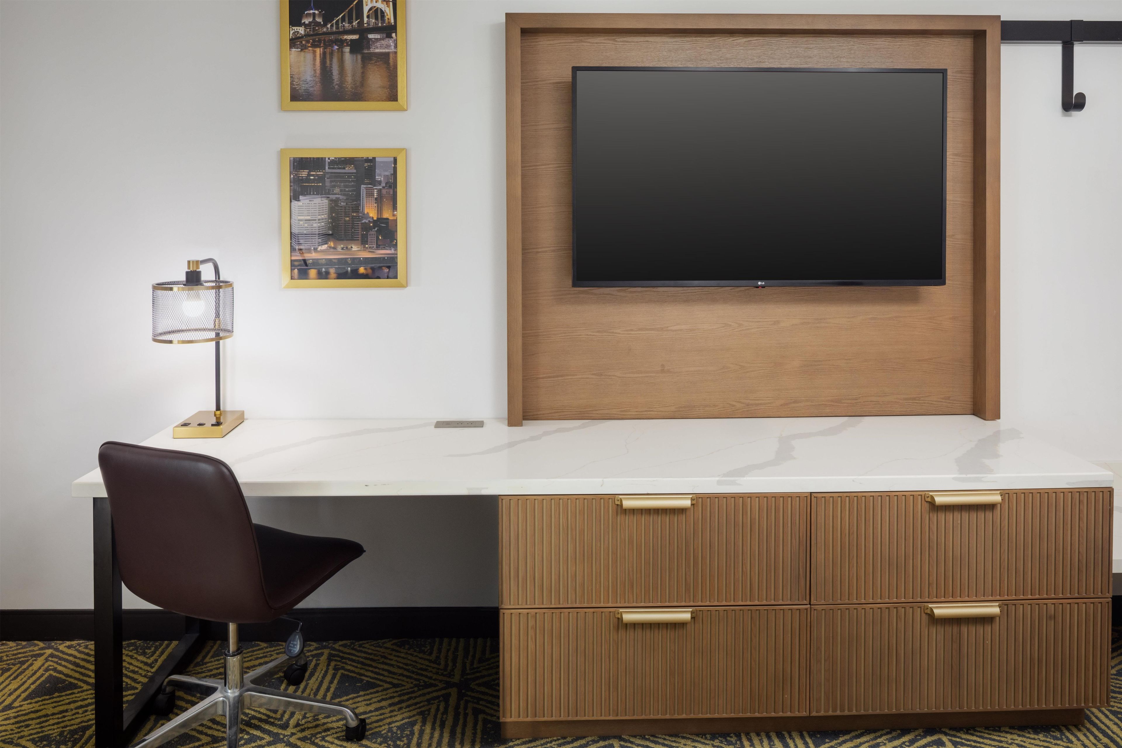 A modern office space with a white desk, a blackboard, and two framed cityscape photographs.