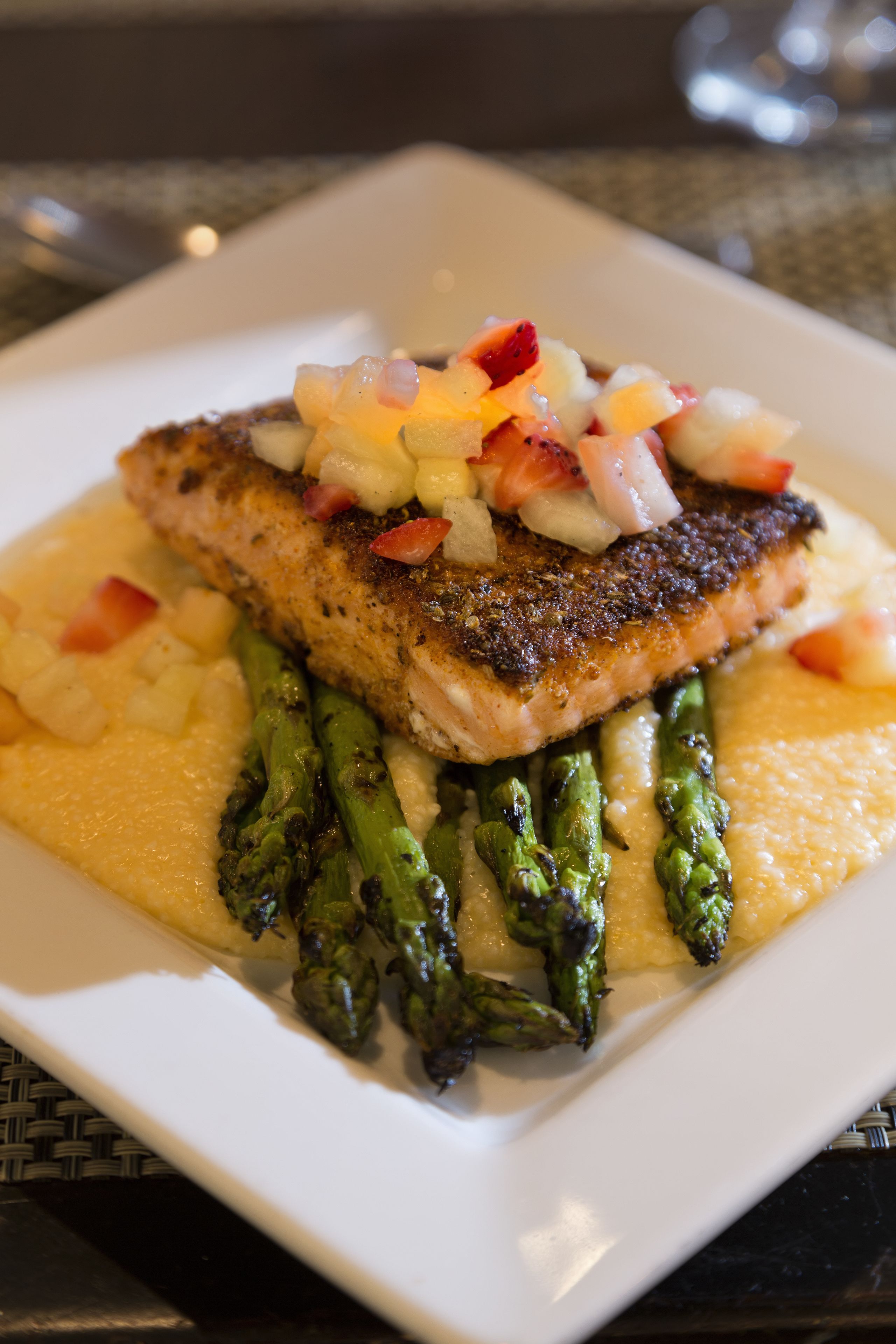 A plate of food with a piece of fish, asparagus, and a creamy sauce.