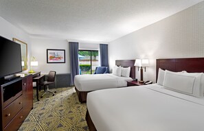 A hotel room with two beds, a desk, a chair, a television, and a window with curtains. - DoubleTree by Hilton Washington Meadow Lands Casino Area (Washington)