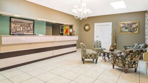A reception area with a counter, chairs, a chandelier, a clock, and a framed picture on the wall.