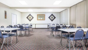 A conference room with tables and chairs, a patterned carpet, and decorative wall mirrors.