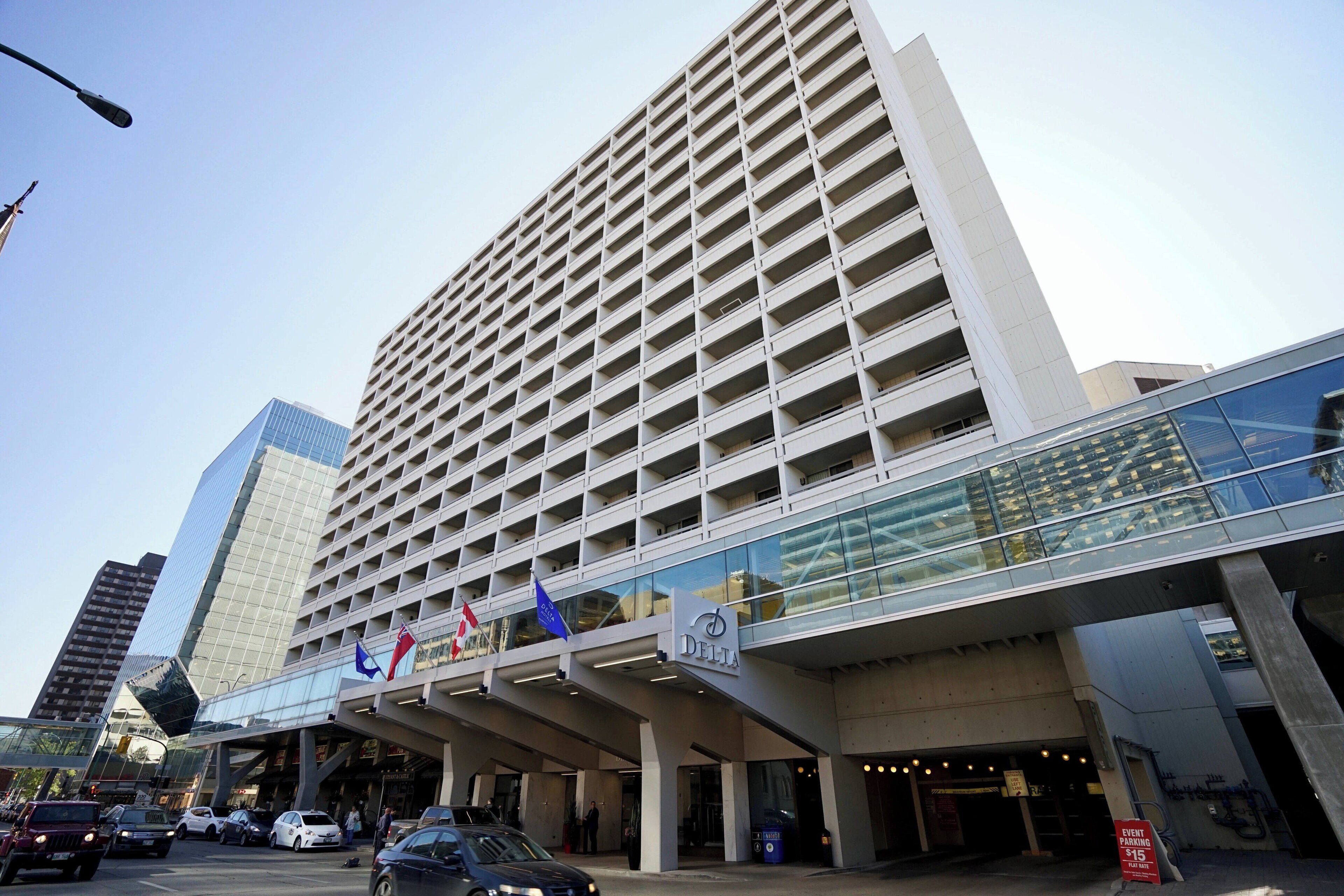 A modern hotel with a prominent glass facade, multiple floors, and a covered entrance area.