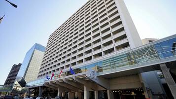 A modern hotel with a prominent glass facade, multiple floors, and a covered entrance area.