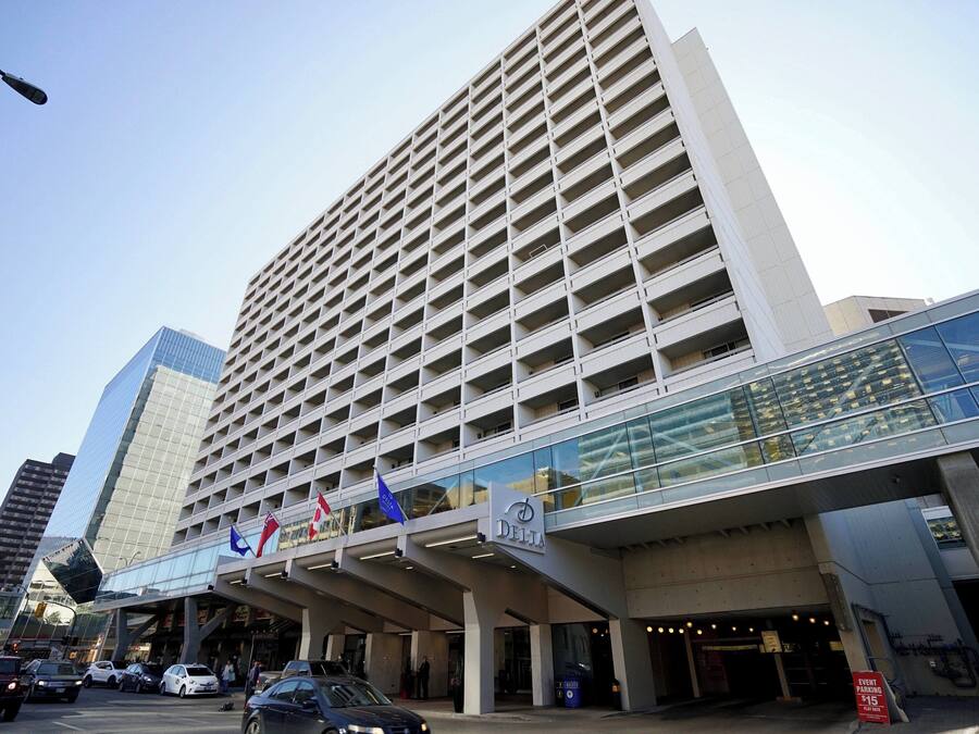 A modern hotel with a prominent glass facade, multiple floors, and a covered entrance area.