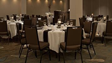 Comedor con mesas redondas, sillas marrones y manteles blancos.