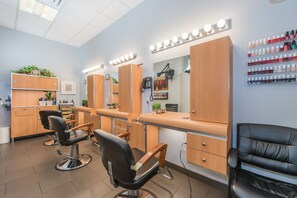 A salon with multiple chairs, wooden cabinets, and a wall of nail polish bottles. - The Lombardy Hotel (New York)