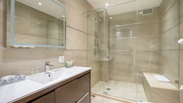 Une salle de bain moderne avec une douche à parois de verre, un grand miroir et un lavabo blanc.