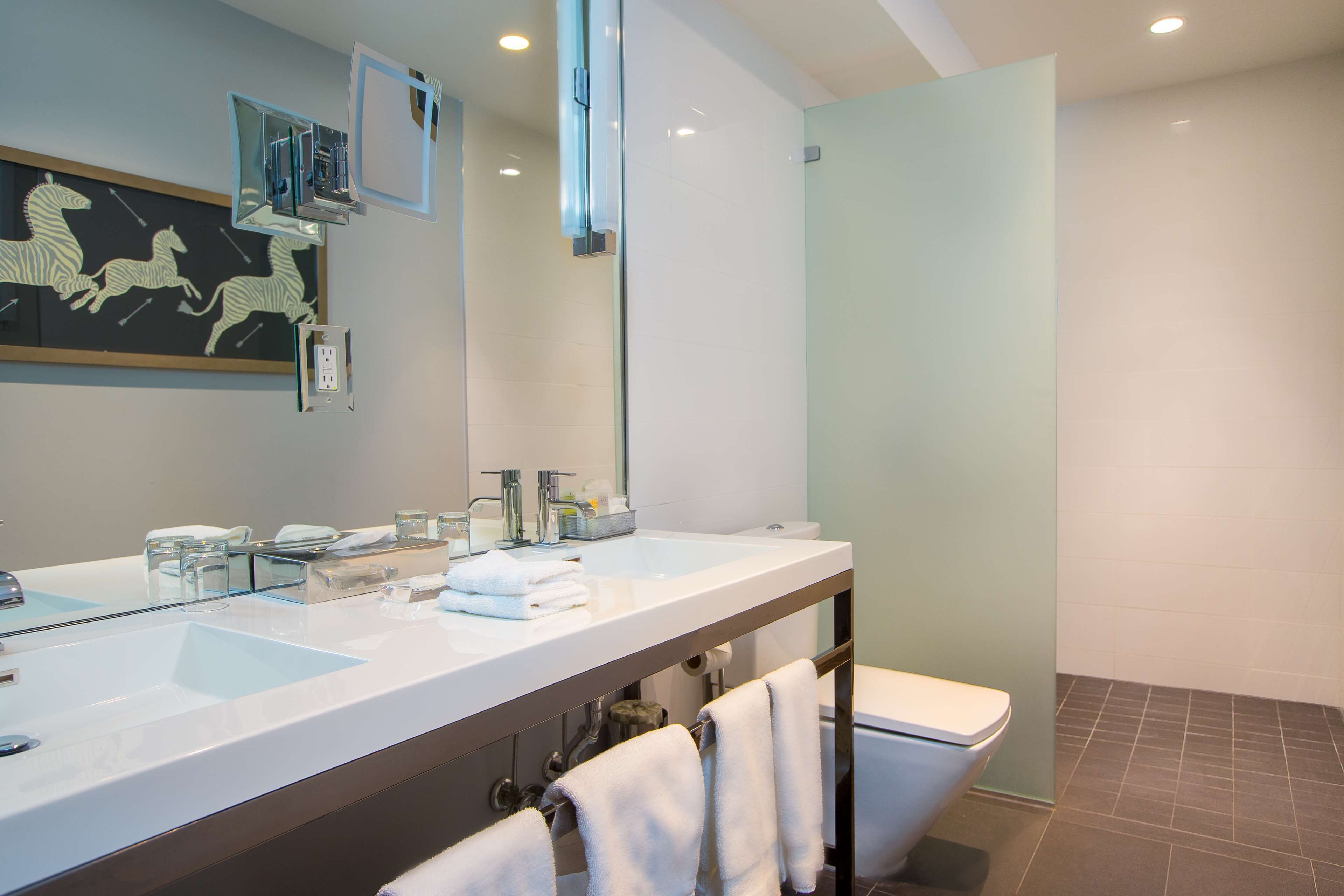 Een moderne badkamer met een grote spiegel, twee wastafels en een toilet.
