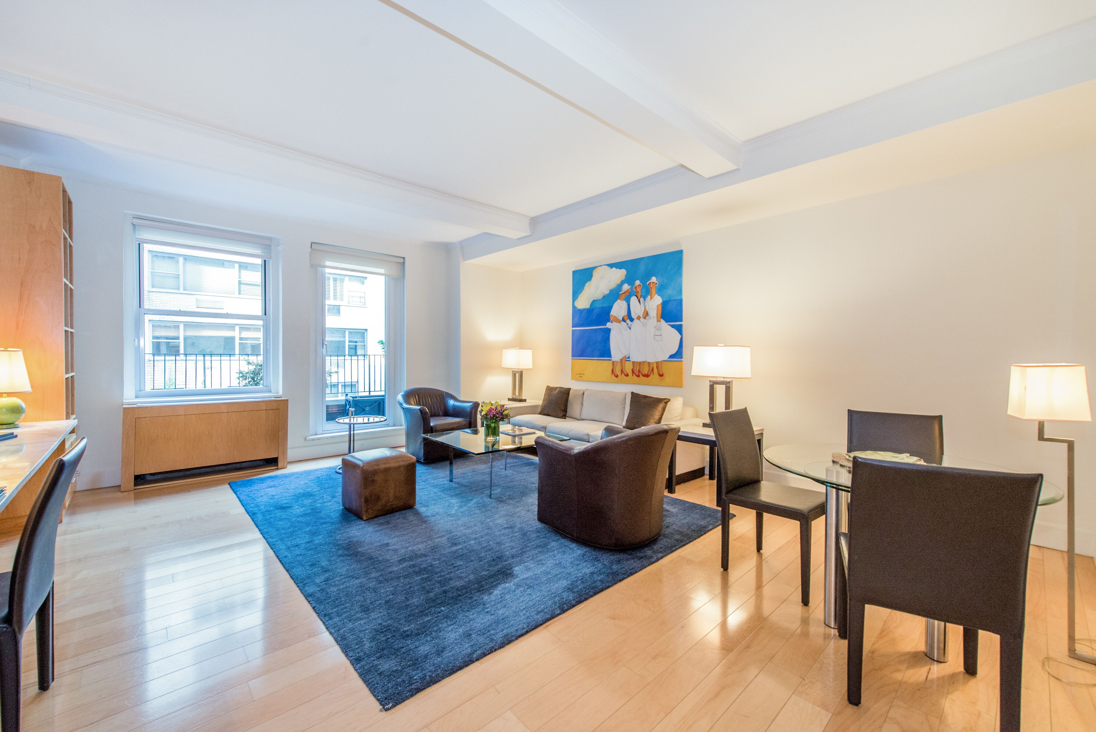 Un salon moderne avec un tapis bleu, un canapé, une table basse et un tableau accroché au mur.