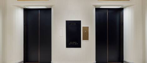 A hallway with two elevators, each marked with a number and a digital display.