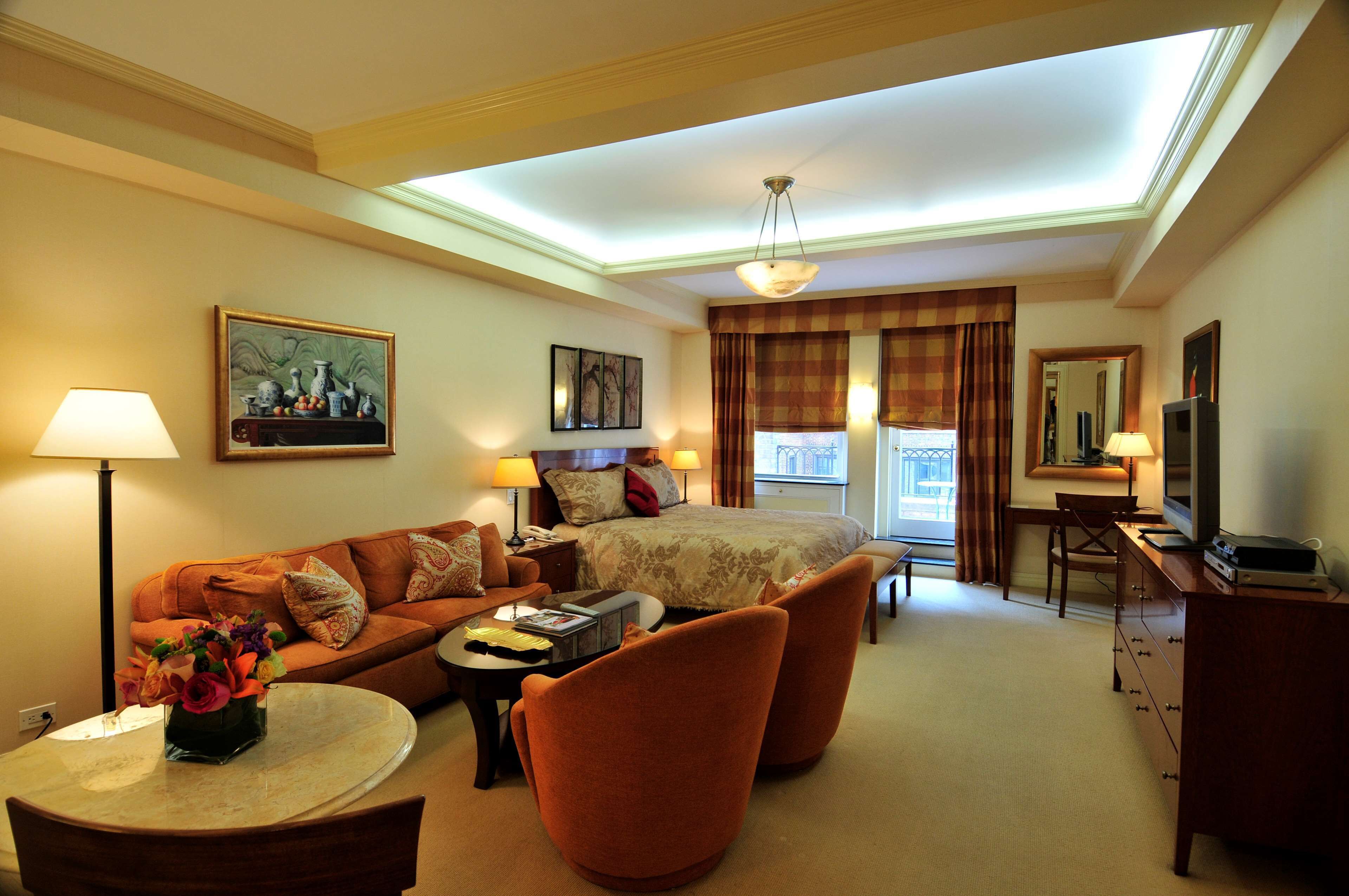 A hotel room with a bed, a sofa, a desk, a TV, and a lamp.
