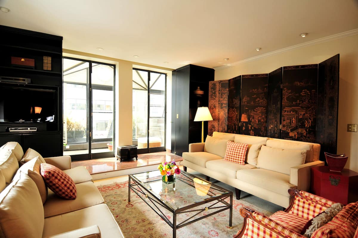 A living room with a sofa, armchairs, a coffee table, and a TV.