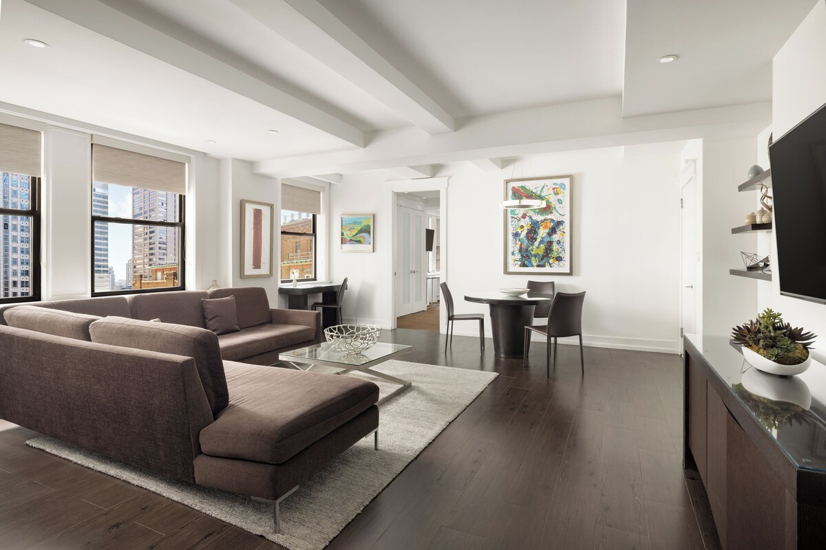 A modern living room with a sectional sofa, a glass coffee table, and a dining area with a table and chairs.