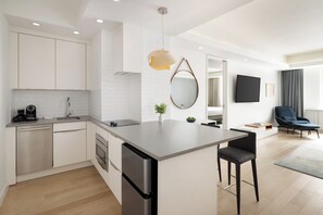 A modern kitchen with a central island, built-in appliances, and a dining area with a flat-screen TV. - The Lombardy Hotel (New York)