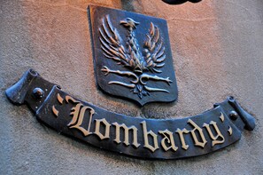 A metal plaque with an eagle emblem and the inscription "Lombardy" on a textured wall. - The Lombardy Hotel (New York)