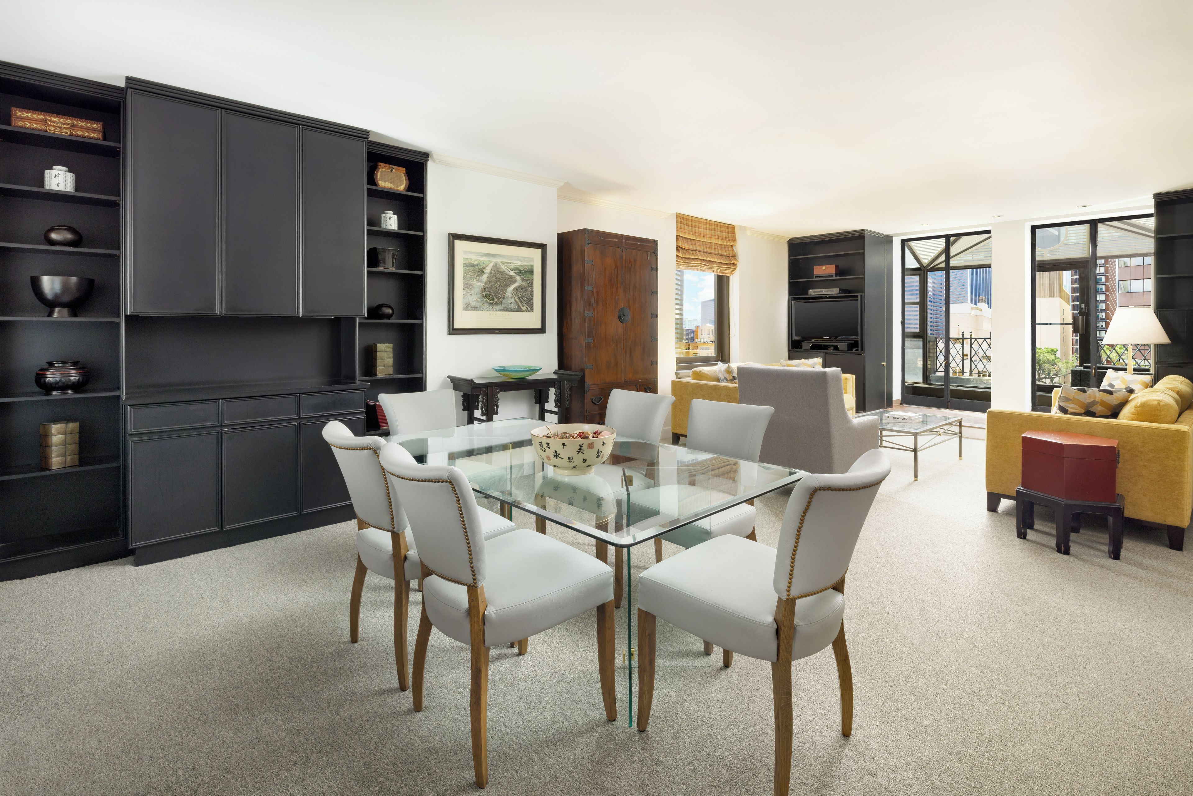 Un salón moderno con una mesa de comedor de cristal, sillas blancas y un sofá amarillo.