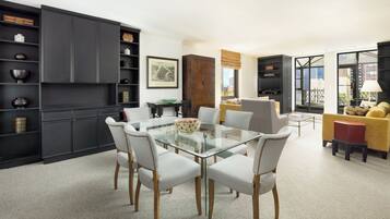 Un salón moderno con una mesa de comedor de cristal, sillas blancas y un sofá amarillo.